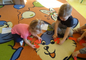 Dwoje dzieci układa obrazek z części w kształcie serca.